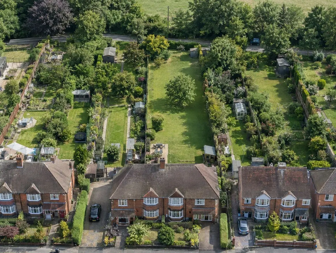 Aerial view of 1930s semi-detached houses with long rear gardens backing onto a lane